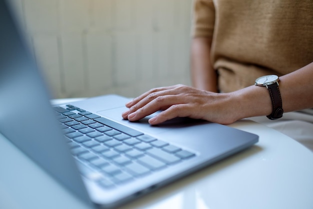 Immagine del primo piano di una donna che lavora e tocca il touchpad del laptop sul tavolo