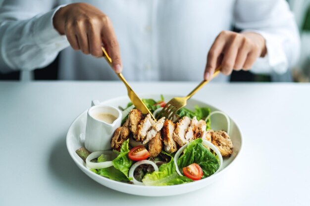 Immagine del primo piano di una donna che mangia insalata di pollo sul tavolo del ristorante