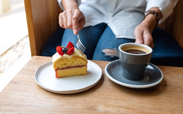 Immagine del primo piano di una donna che mangia la torta e che beve caffè nella caffetteria