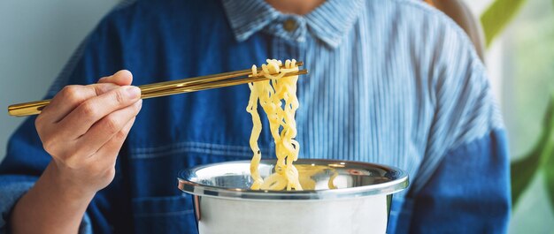 Immagine del primo piano di una donna che mangia noodle istantanei in stile asiatico a casa