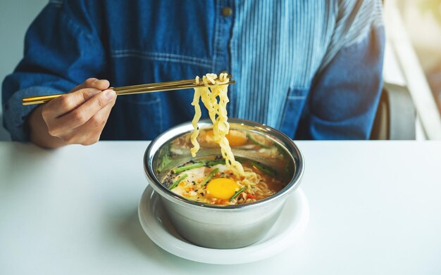 Immagine del primo piano di una donna che mangia noodle istantanei in stile asiatico a casa