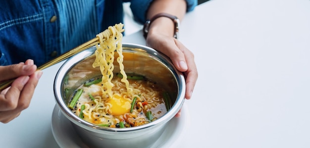 Immagine del primo piano di una donna che mangia noodle istantanei in stile asiatico a casa