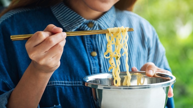 Immagine del primo piano di una donna che mangia spaghetti istantanei in stile asiatico a casa