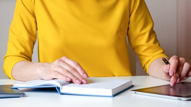 Immagine del primo piano di una donna che scrive su un taccuino in bianco bianco