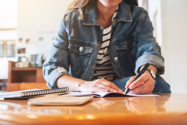 Immagine del primo piano di una donna che scrive su un taccuino sul tavolo