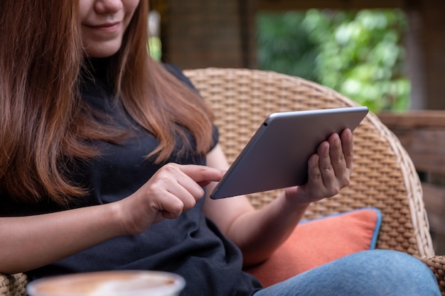 Immagine del primo piano di una donna che tiene e che indica al tablet pc in mezzo alla natura