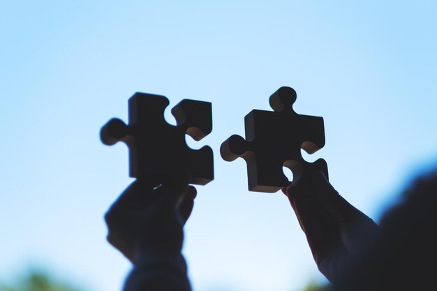 Immagine del primo piano di una donna che tiene e mette insieme un pezzo di puzzle di legno