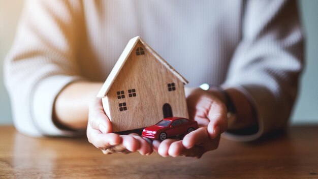 Immagine del primo piano di una donna che tiene e mostra il modello di figura dell'auto e il modello di casa in legno