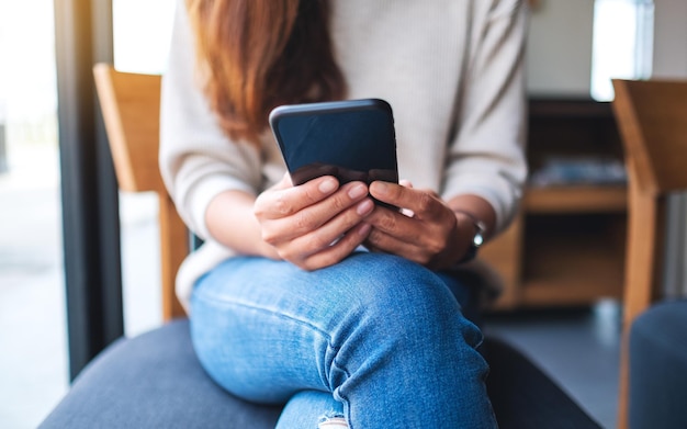 Immagine del primo piano di una donna che tiene e utilizza lo smartphone