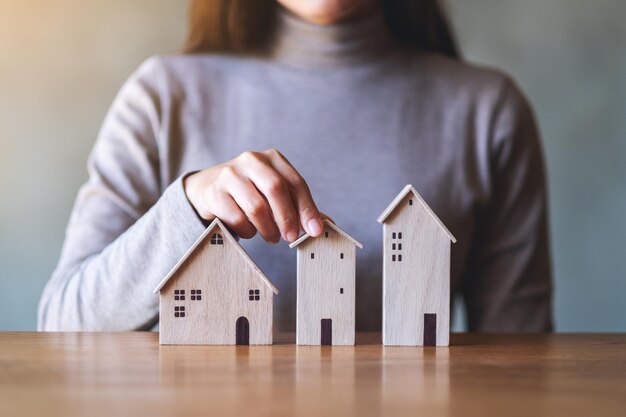 Immagine del primo piano di una donna che tiene i modelli di casa in legno sul tavolo