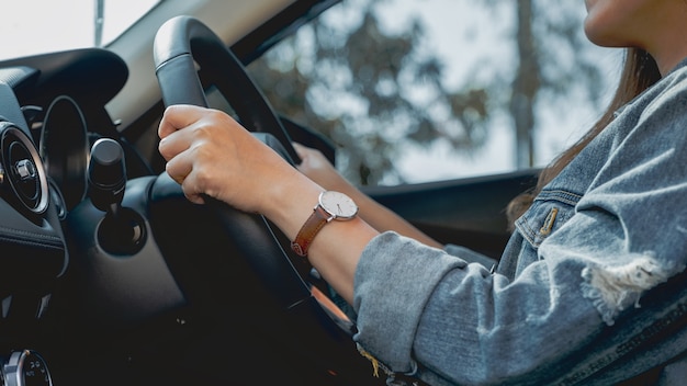 Immagine del primo piano di una donna che tiene il volante mentre guida un'auto