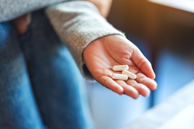 Immagine del primo piano di una donna che tiene in mano le capsule bianche della medicina