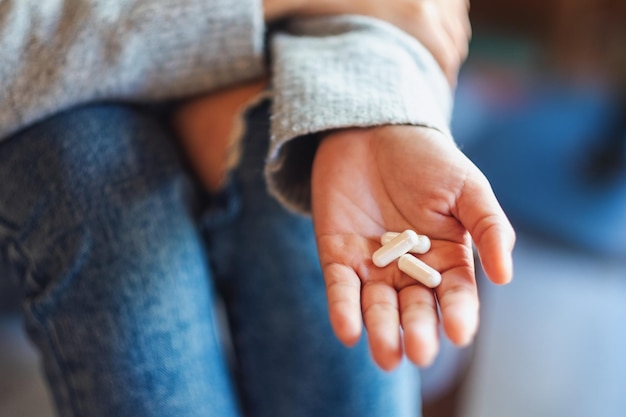 Immagine del primo piano di una donna che tiene in mano le capsule bianche della medicina