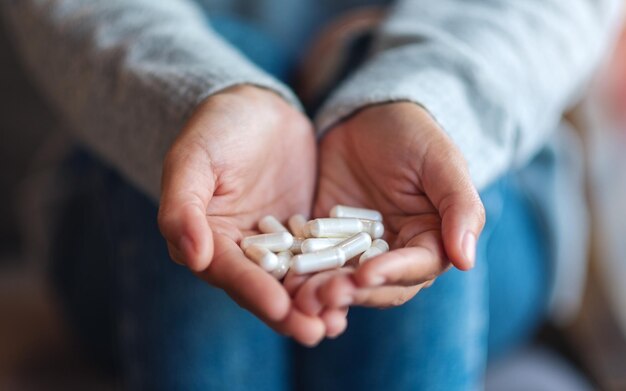 Immagine del primo piano di una donna che tiene in mano le capsule bianche della medicina