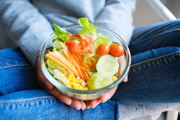 Immagine del primo piano di una donna che tiene in mano una ciotola di insalata di verdure miste fresche
