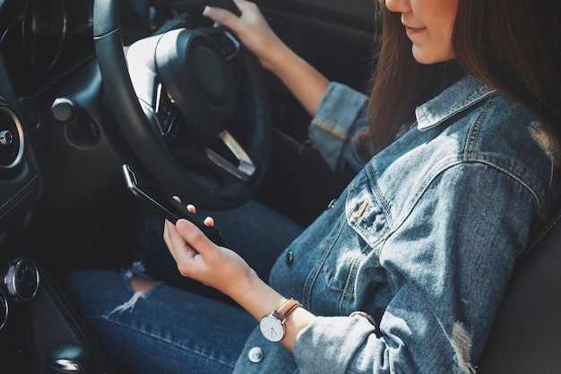 Immagine del primo piano di una donna che usa il telefono cellulare mentre guida un'auto