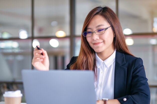 Immagine del primo piano di una donna d'affari che guarda il laptop mentre lavora in ufficio