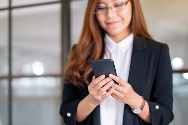 Immagine del primo piano di una donna d'affari che tiene e usa il cellulare