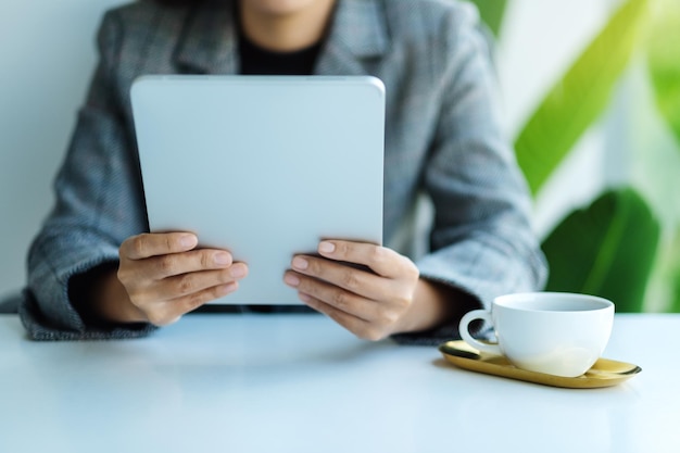 Immagine del primo piano di una donna d'affari che tiene e usa un tablet pc in ufficio