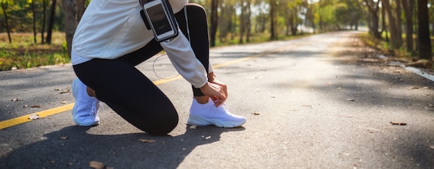 Immagine del primo piano di una donna runner che allaccia i lacci delle scarpe e si prepara per correre nel parco cittadino