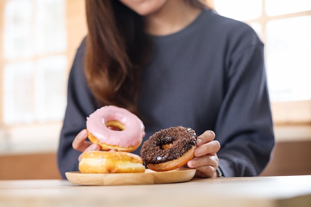 Immagine del primo piano di una giovane donna che tiene e mangia le ciambelle a casa