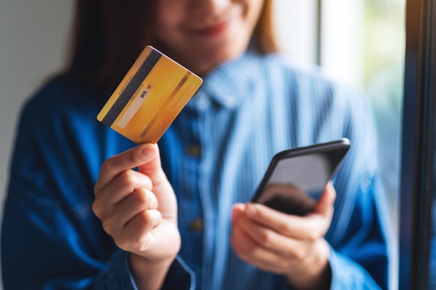 Immagine del primo piano di una giovane donna che utilizza la carta di credito per l'acquisto e lo shopping online sul telefono cellulare