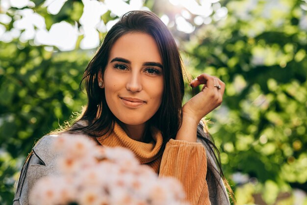 Immagine del primo piano di una giovane donna felice con un mazzo di fiori rosa in una giornata di sole nel parco Bella donna ha ricevuto un regalo un mazzo di fiori dal suo fidanzato nella strada della città