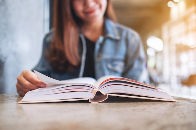 Immagine del primo piano di una giovane donna seduta e leggendo un libro