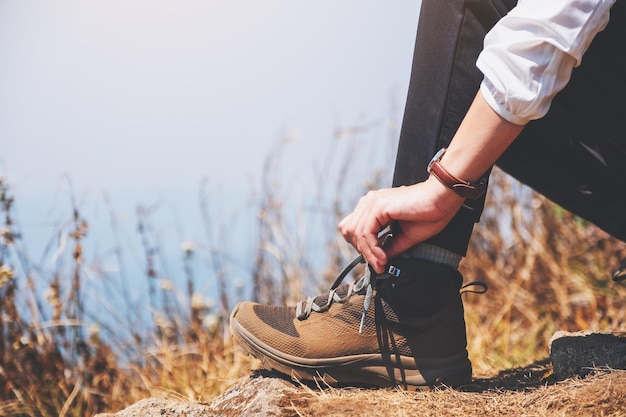 Immagine del primo piano di una viandante che allaccia i lacci delle scarpe e si prepara per il trekking sulla cima della montagna