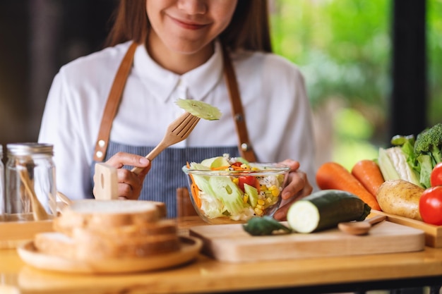 Immagine del primo piano di uno chef femminile che cucina e mangia insalata di verdure miste fresche in cucina