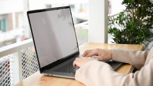 Immagine del primo piano Imprenditrice che lavora a distanza nello spazio di coworking della caffetteria digitando sul laptop