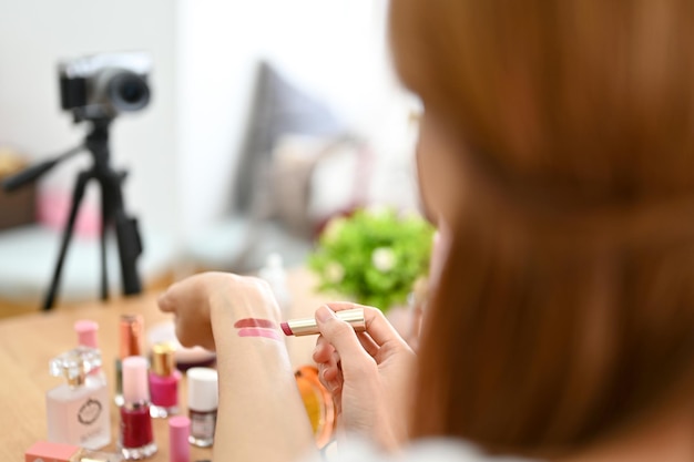 Immagine del primo piano Influencer del blogger di bellezza femminile che prova il rossetto sulla sua mano