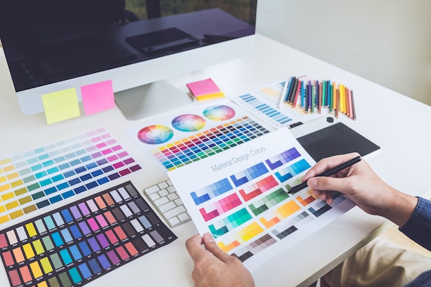 Immagine del progettista grafico creativo femminile che lavora alla selezione di colore e che attinge la tavola del grafico