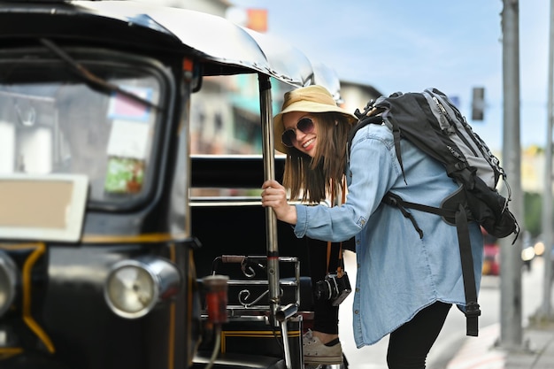 Immagine del turista caucasico che entra nel taxi locale di Tuk Tuk per esplorare la città in Tailandia