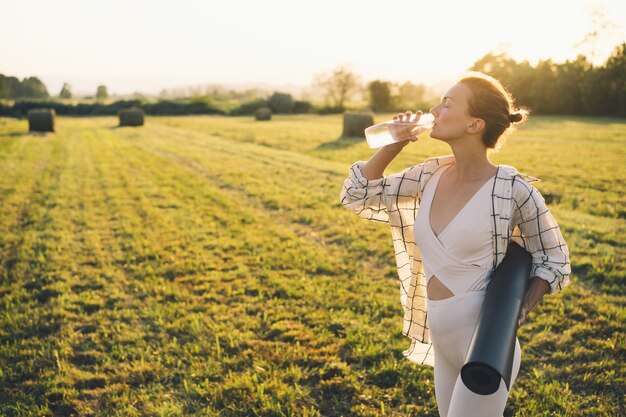 Immagine dell'ispirazione yoga sulla natura La giovane donna con il tappetino da yoga si prepara a praticare lo yoga all'aperto