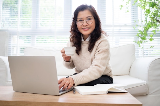 Immagine della donna d'affari asiatica senior che lavora a casa