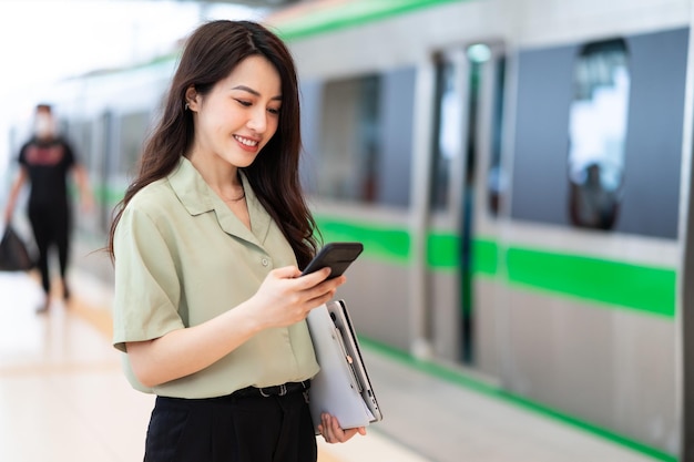 Immagine della donna di affari asiatica che utilizza il telefono al treno