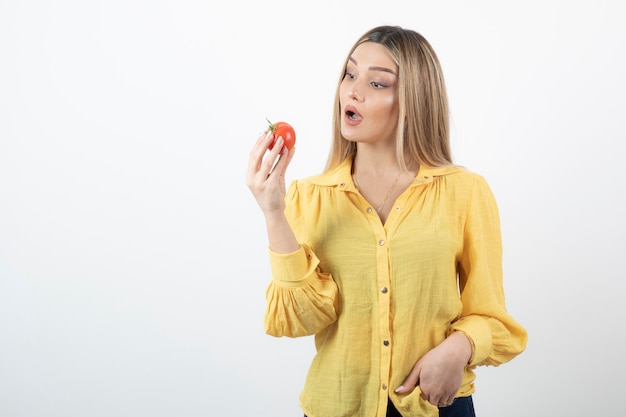 Immagine della donna sorpresa guardando il pomodoro rosso su bianco.