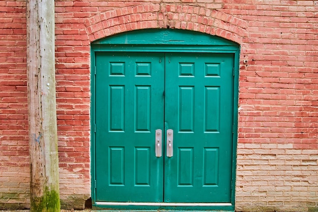 Immagine della doppia porta verde del vicolo con mattoni rossi