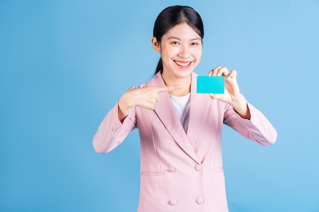Immagine della giovane donna asiatica che tiene la carta di credito della carta di credito sullo sfondo