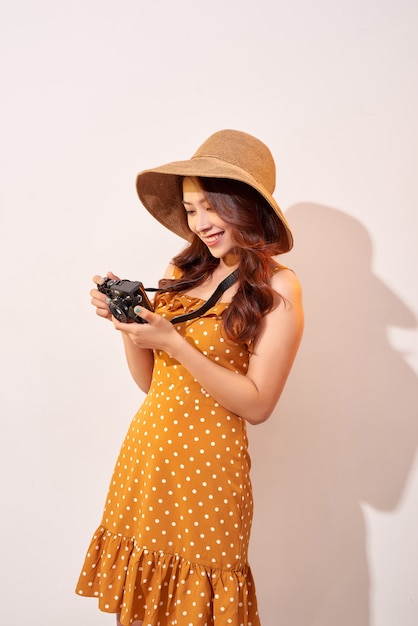 Immagine della giovane donna del fotografo isolata sopra la macchina fotografica beige della tenuta della parete della parete.