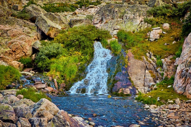 Immagine della grande cascata con massi di licheni