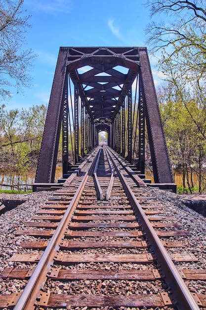 Immagine della verticale dei binari del treno con un ponte in acciaio sul fiume