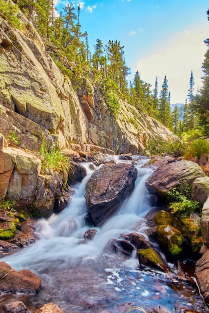 Immagine della verticale della cascata attraverso grandi massi in montagna con rocce di licheni