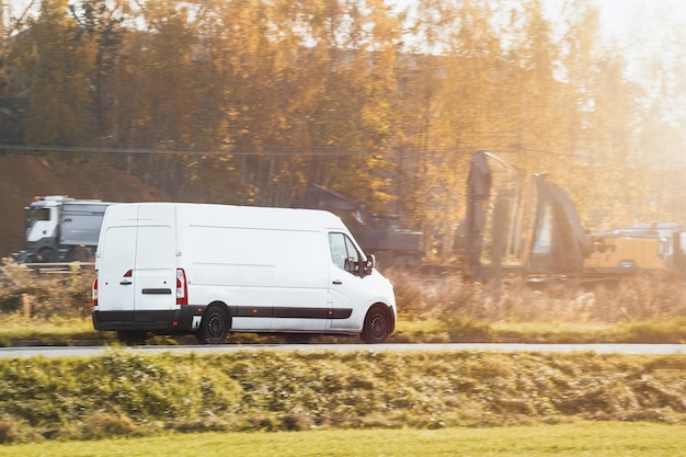 Immagine di banner di un furgone corriere di merci bianco e moderno che si muove velocemente sulla strada autostradale verso la città e la periferia urbana Un piccolo autobus che guida su un'autostrada