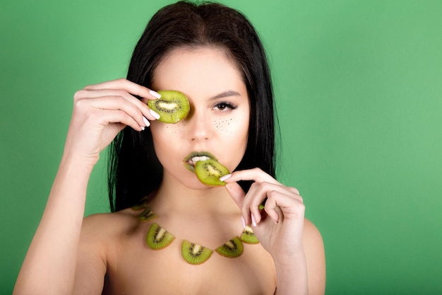 Immagine di bella donna senza camicia che posa con il kiwi. Foto creativa