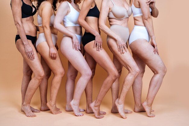 Immagine di bellezza di un gruppo di donne con età, pelle e corpo diverse che posano in studio per un servizio fotografico positivo per il corpo. Modelli femminili misti in lingerie su sfondi colorati