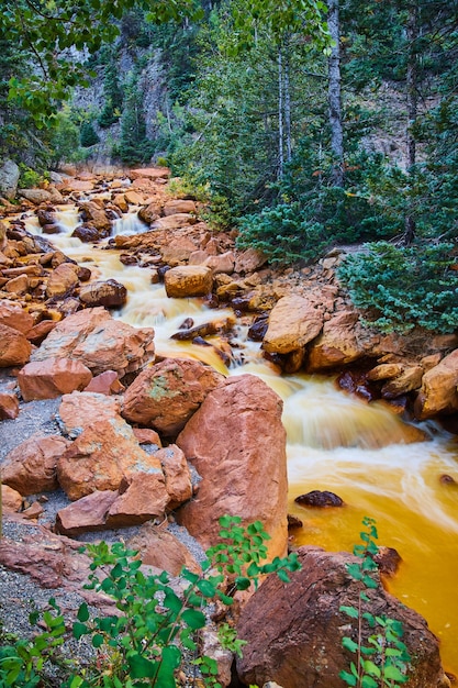 Immagine di cascate che scendono lungo un piccolo fiume fiancheggiato da grandi rocce rosse