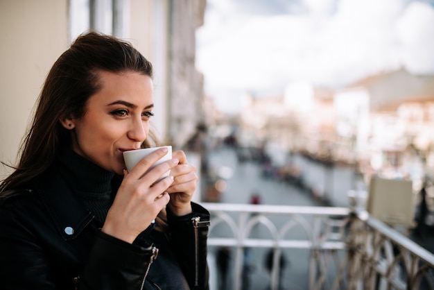 Immagine di Close-up di una ragazza carina rilassante sulla terrazza con una tazza di caffè.