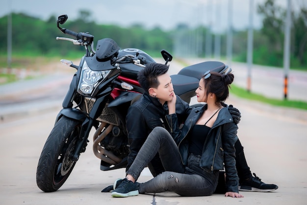 Immagine di coppia asiatica motociclista con moto sulla stradaBello uomo e bella donna indossare pelle nera per il guidatore sulla stradaPopolo della ThailandiaDolce nuova coppia